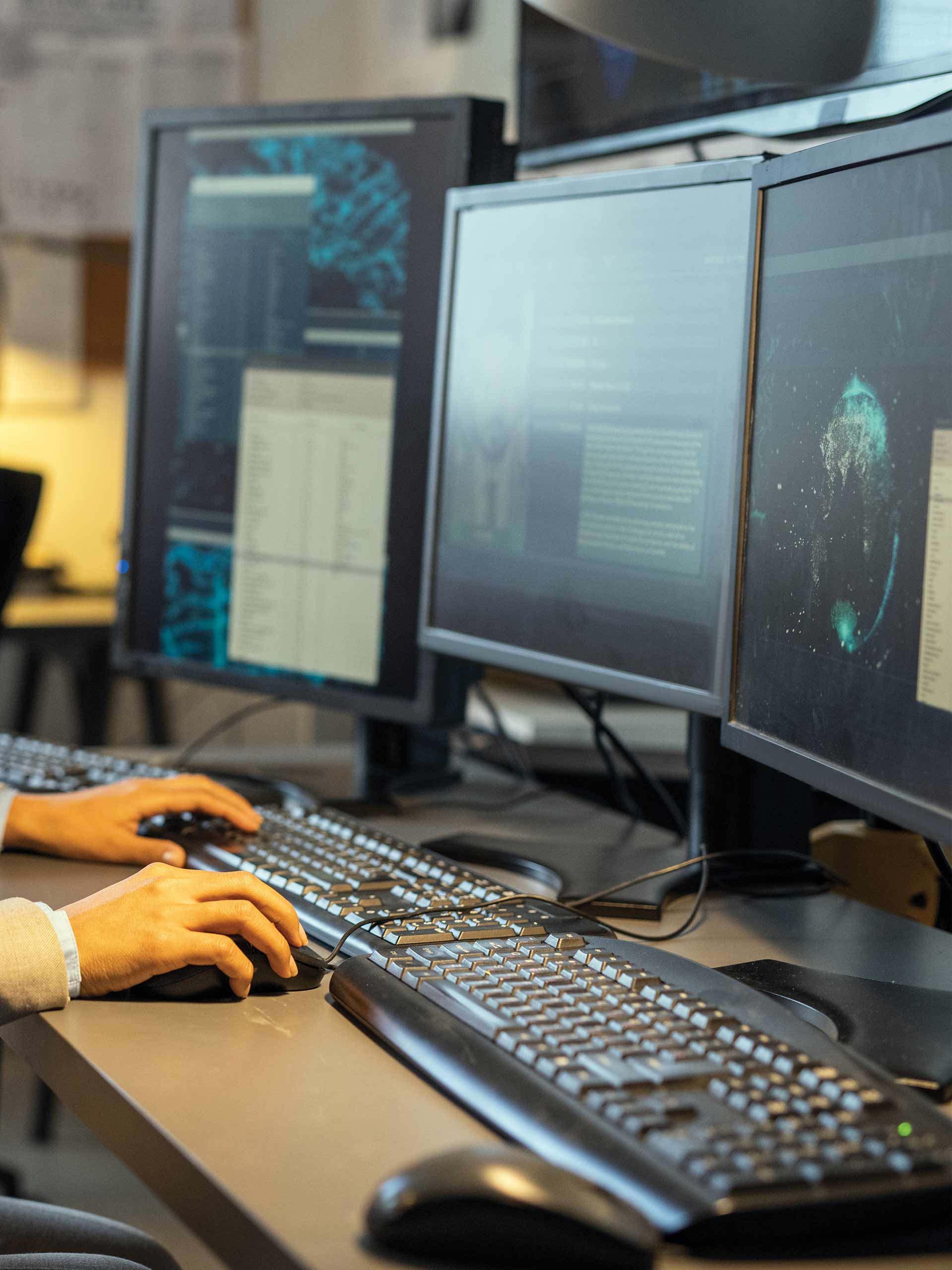 Foto di tecnico informatico mentre svolge assistenza da remoto utilizzando più pc con più monitor